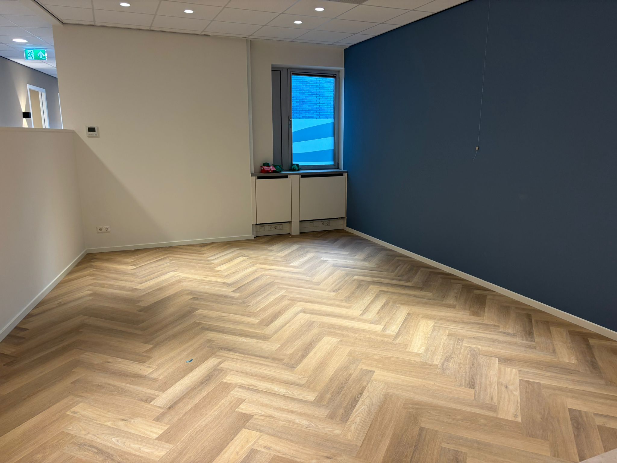 Afgewerkte werkruimte met blauwe accentwand en visgraatvloer